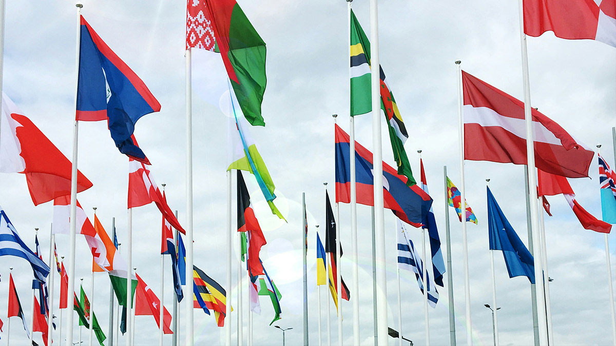Die vielen verschiedenen abgebildeten Flaggen symbolisieren die vielfältigen Chancen und Möglichkeiten der globalen und interkulturellen Arbeit.